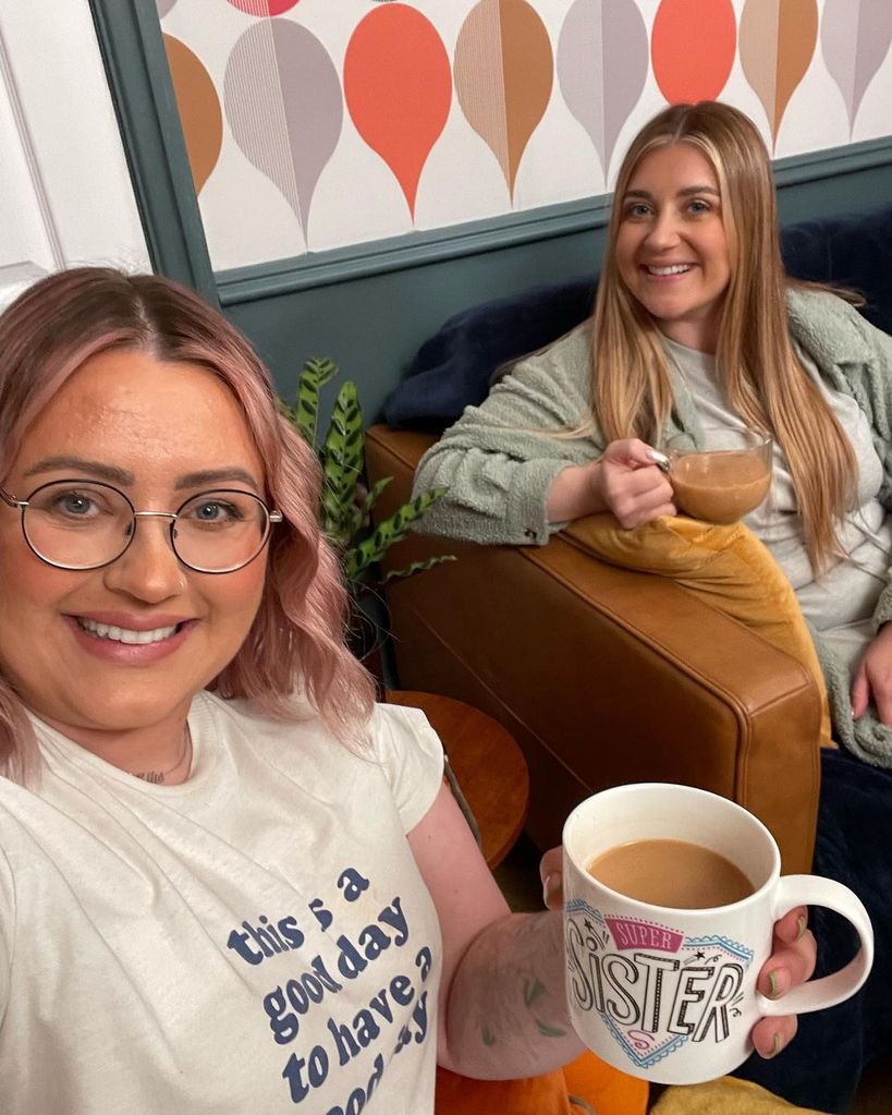 Ellie and Izzi Warner with cups of tea on the sofa