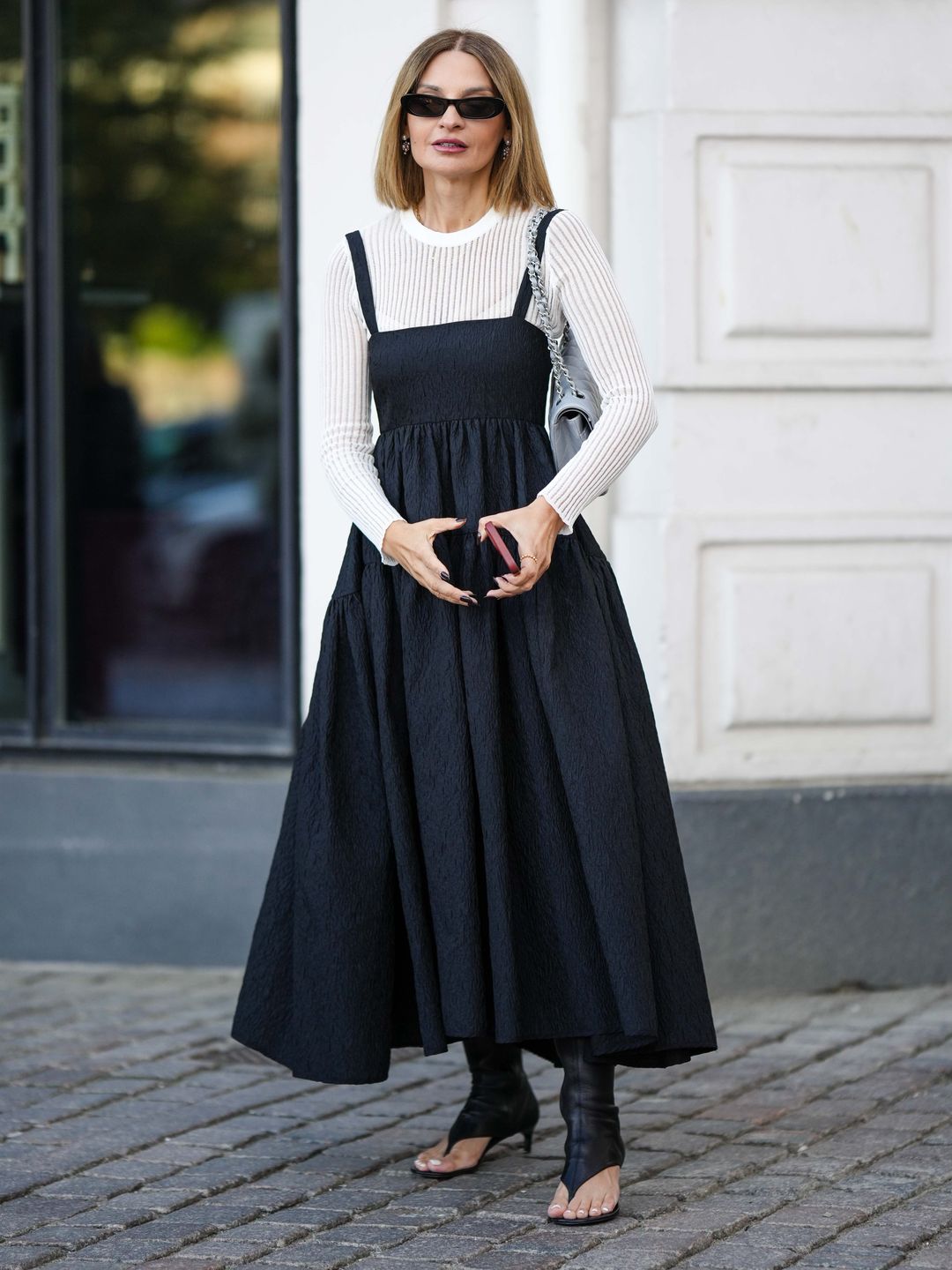 influencer with a black dress layered over a white long sleeve