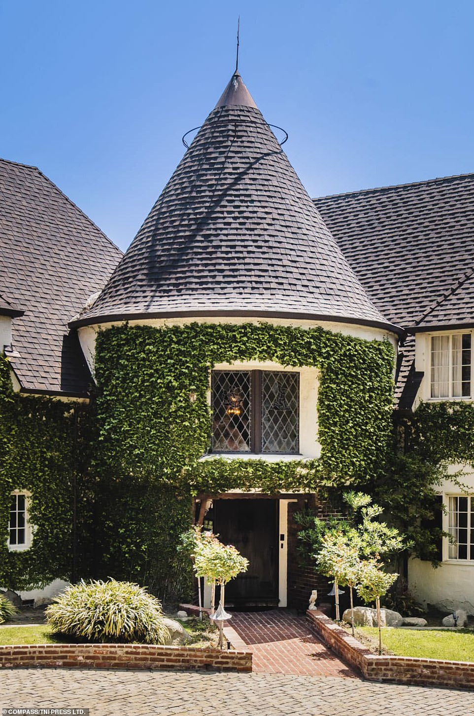 The turret that anchors the center of the house and acts as its front entry point. Stained-glass windows with colorful character in their centers can be seen directly above the door
