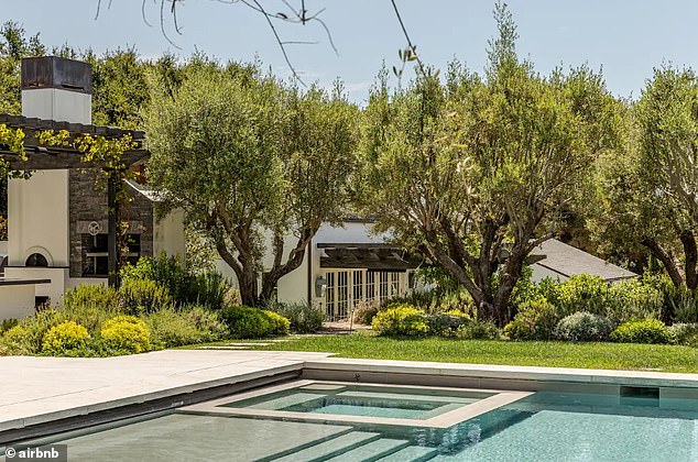 The clean white home is decorated with pristine landscaping and a pool
