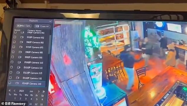 Young quickly stands and backs away from the agents with his hands raised in a surrendering gesture