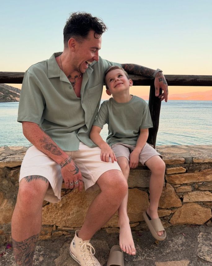 Danny Jones sitting on a wall with his young son