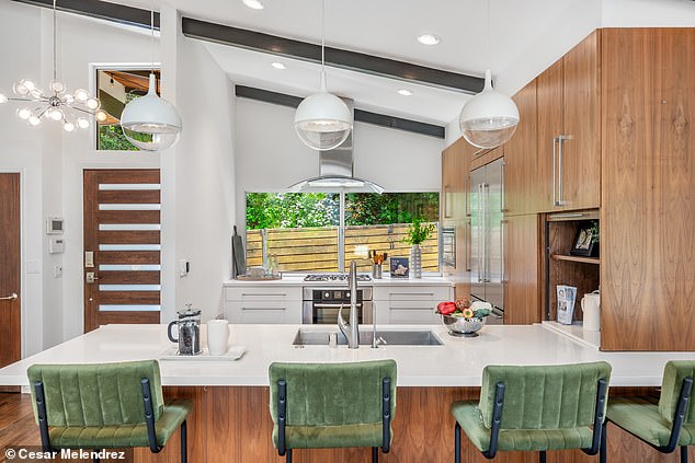 The chef's kitchen includes white marble countertops that match the drawers built in next to the stainless steel oven. The island, cabinets and lights were already in the home prior to it being put on the market. However, like the living room, the wooden beams that were hardly noticeable in the kitchen have been painted black