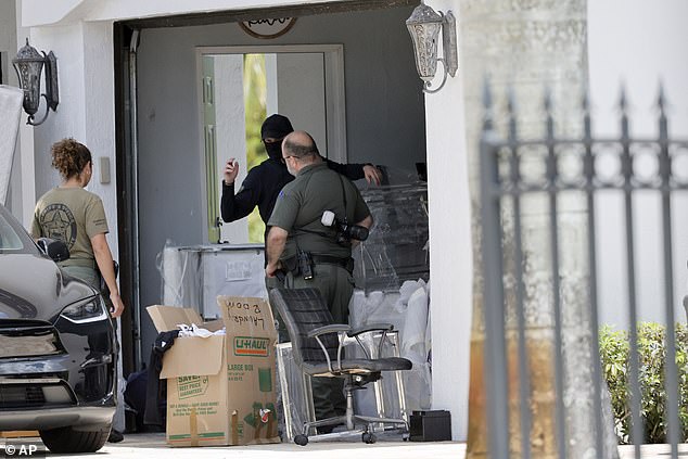 Broward Sheriff's Office personnel move items in the garage at Sean Kingston's Southwest Ranches, Florida, home