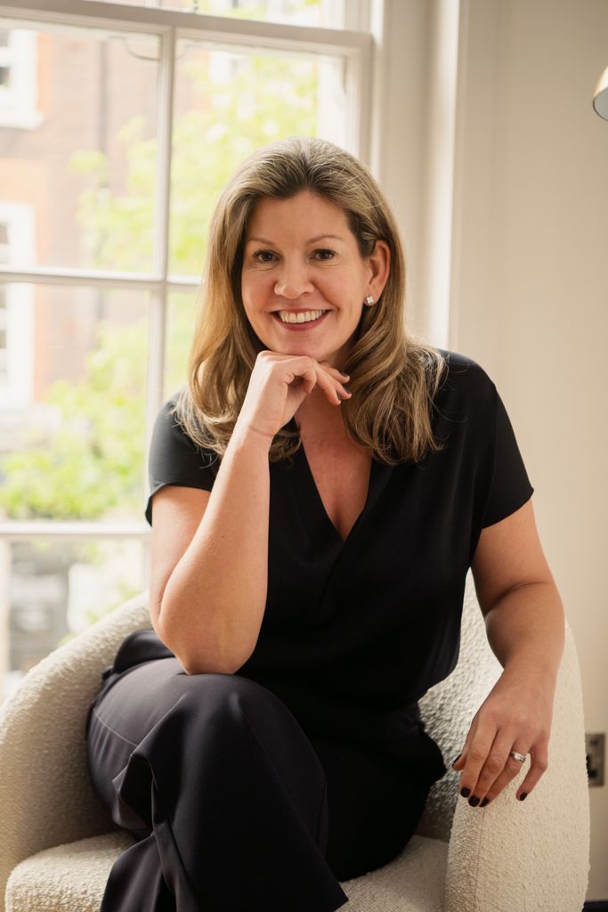 Woman smiling in smart clothes in front of a bright window