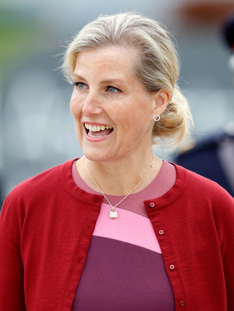 woman smiling in pink dress and red cardigan