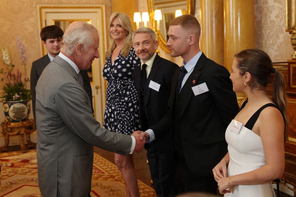 Penny Lancaster in a flattering wrap dress with line up of people talking to King Charles