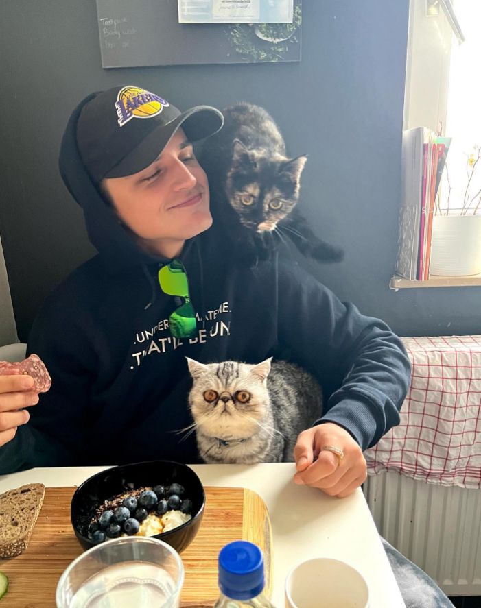 Nikita Kuzmin sat at a dining table with his two cats