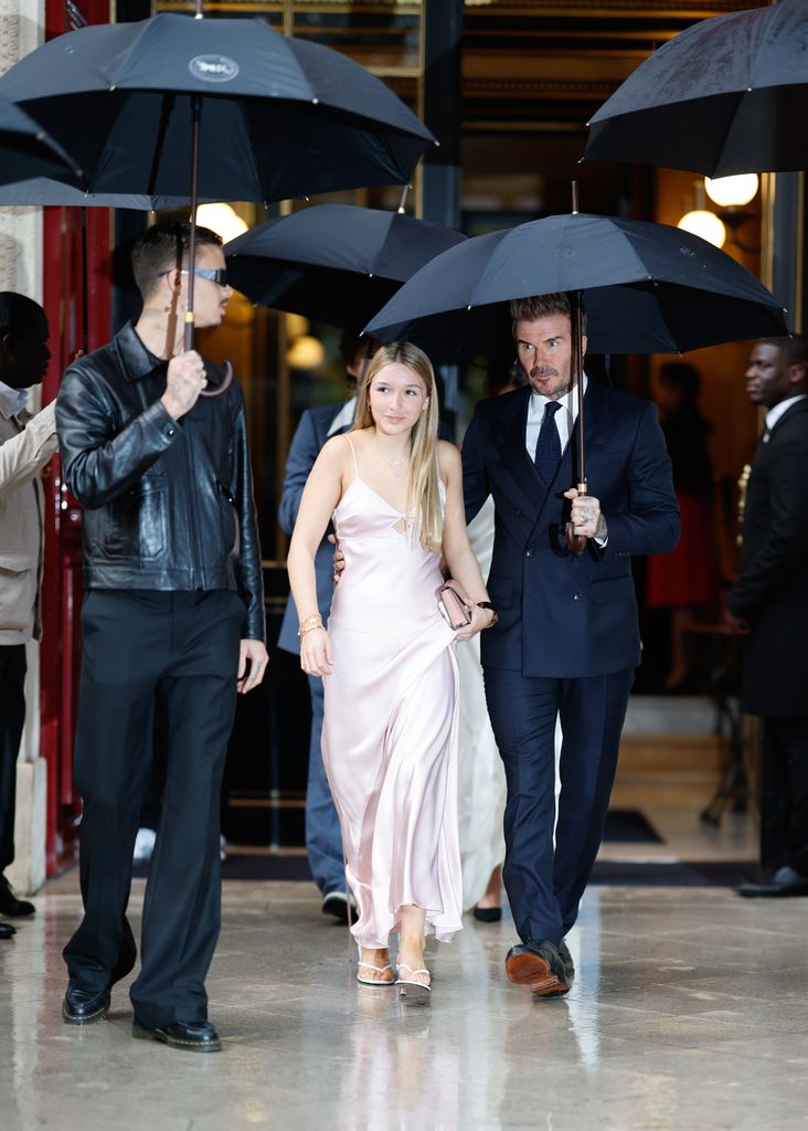 Harper wore a blush gown in the rain, walking with David and Brooklyn Beckham under umbrellas. Her delicate, flowy dress contrasted playfully with the weather, showcasing her stylish confidence.