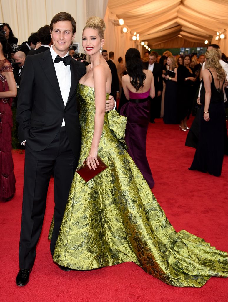 Ivanka wears a metallic green strapless gown with a dramatic train. Her hair is in an updo, and she's paired with her husband in a tuxedo on the red carpet.