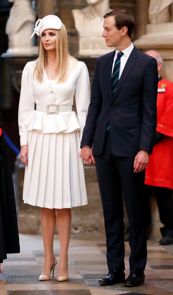 Ivanka wears a sophisticated white outfit with pleats and a peplum waist. A matching white hat completes the vintage-inspired look, as she stands next to her husband Jared Kushner wearing a suit and green striped tie in Westminster Abbey