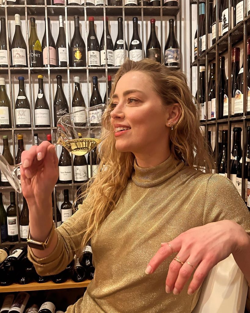 Amber Heard drinking white wine in a wine bar 