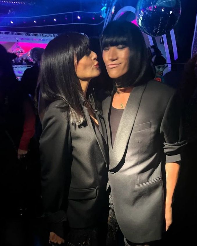 Claudia Winkleman kissing Carlos Gu on the cheek - both wear identical black outfits