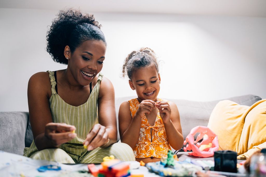 mother and her daughter enjoying their time together, playing with playdough at home.