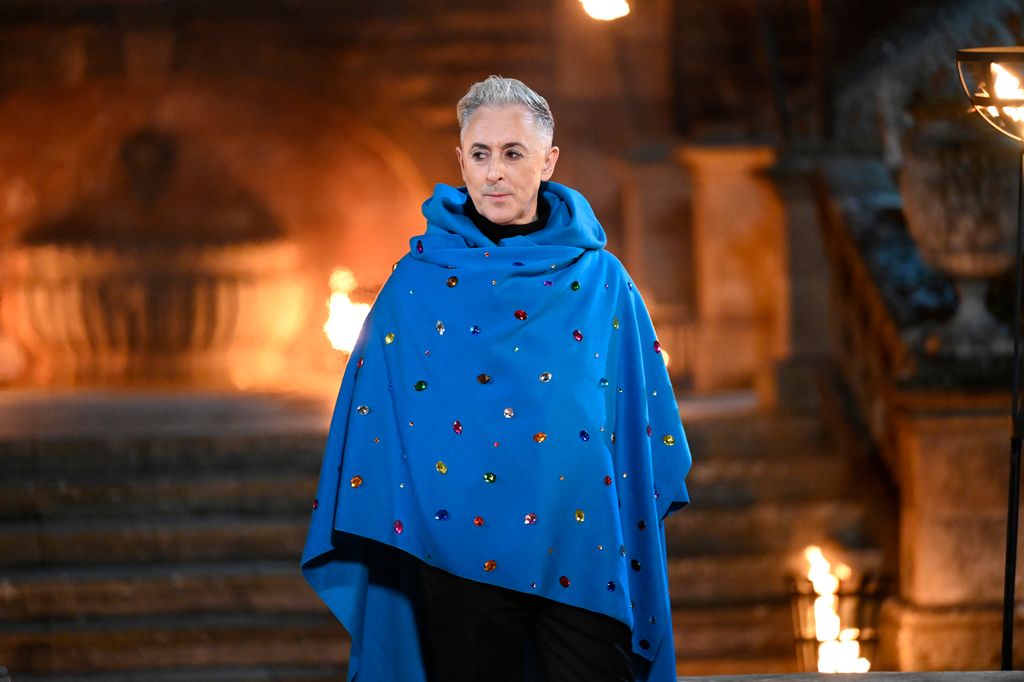 Alan Cumming in a blue cloak