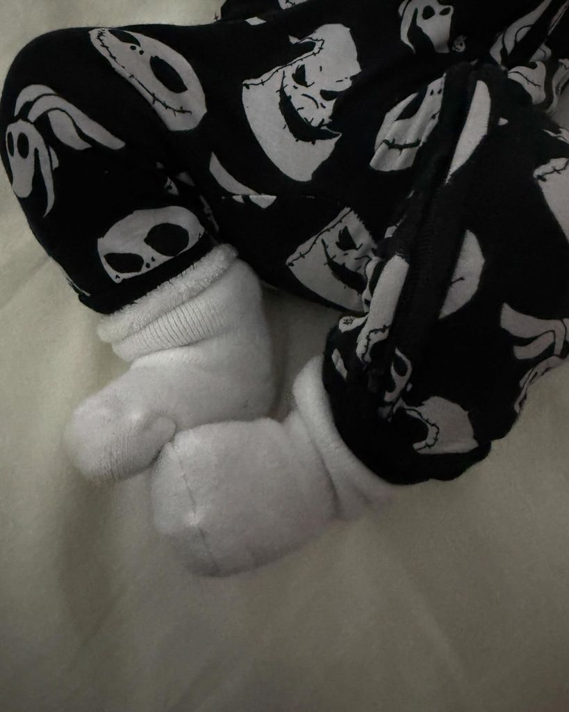 Photo of a baby's feet with the baby wearing a halloween print onesie 