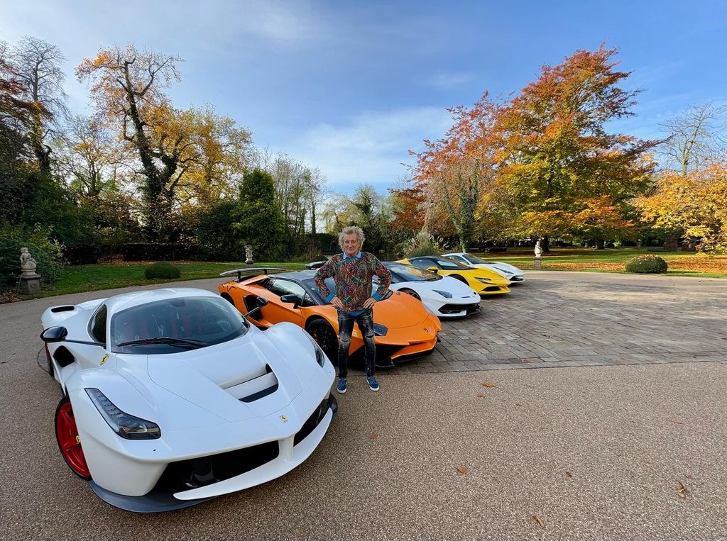 Sir Rod Stewart posing in front of car collection 