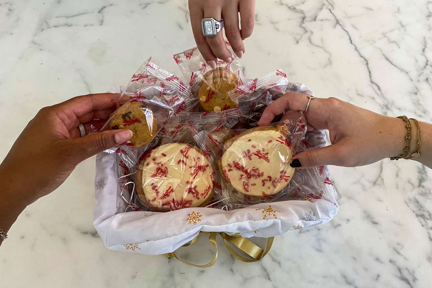 People grabbing cookies from a Mrs. Fields Share the Joy Basket 