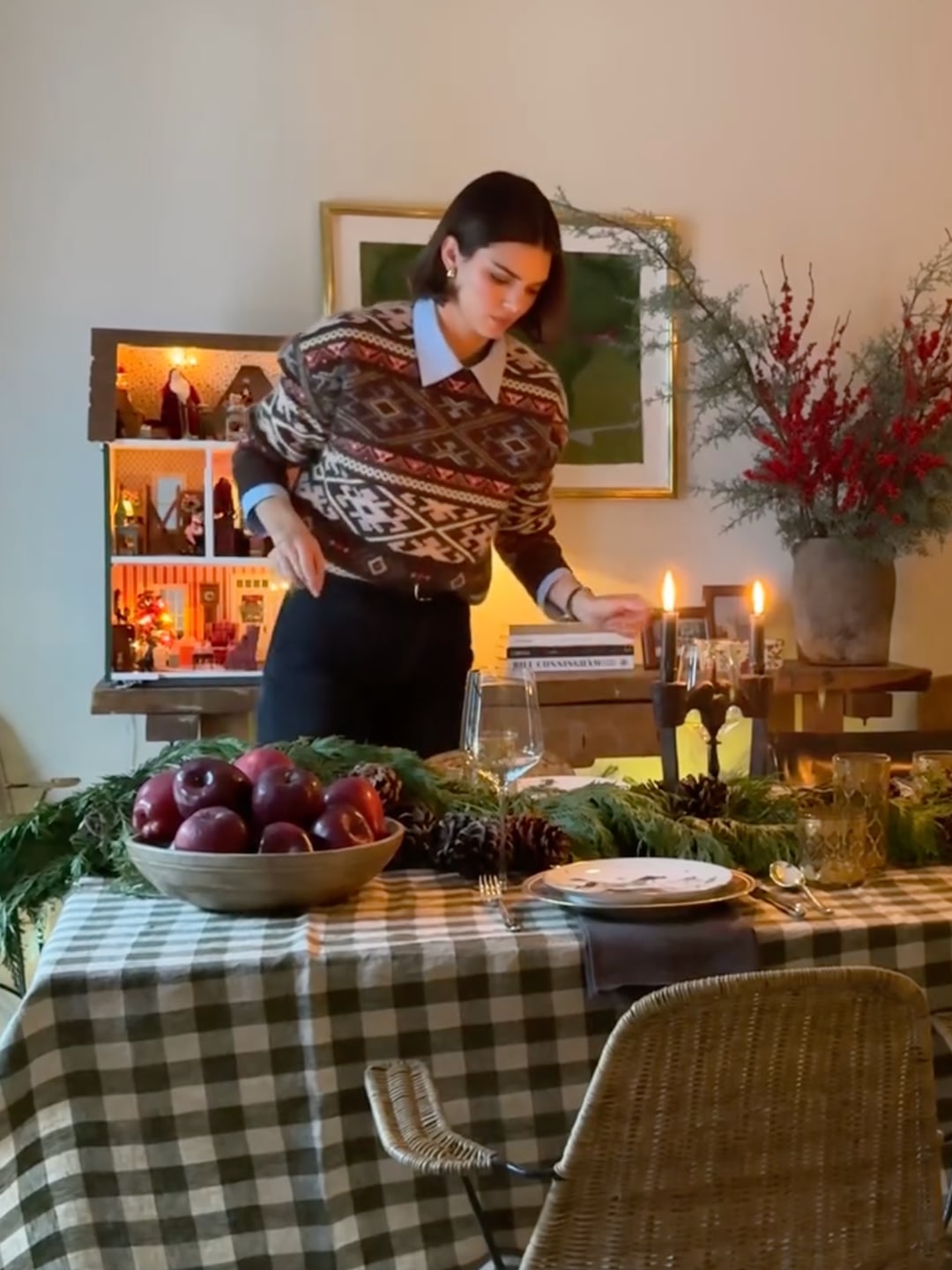 Kendall Jenner's plaid tablecloth, pinecones, and greenery paired perfectly with her Nordic sweater and blue shirt. Festive hosting at its best.