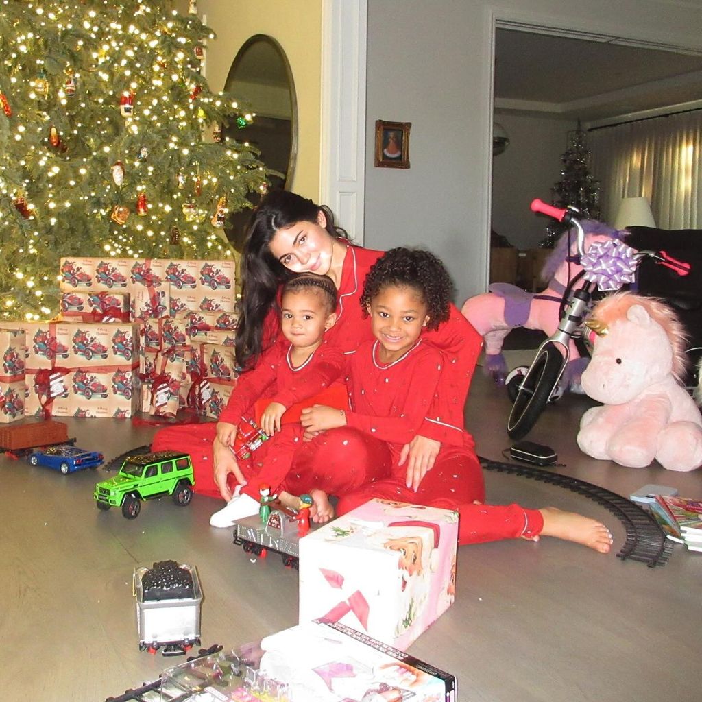 Kylie Jenner sitting on the floor with Stormi and Aire surrounded by Christmas presents