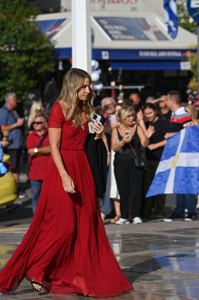 Chrysi Vardinogianni in a red dress holding her phone