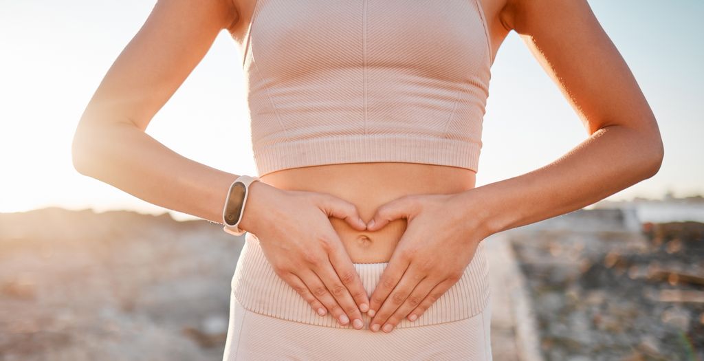 Woman in pink activewear making a heart on her stomach with her hands 