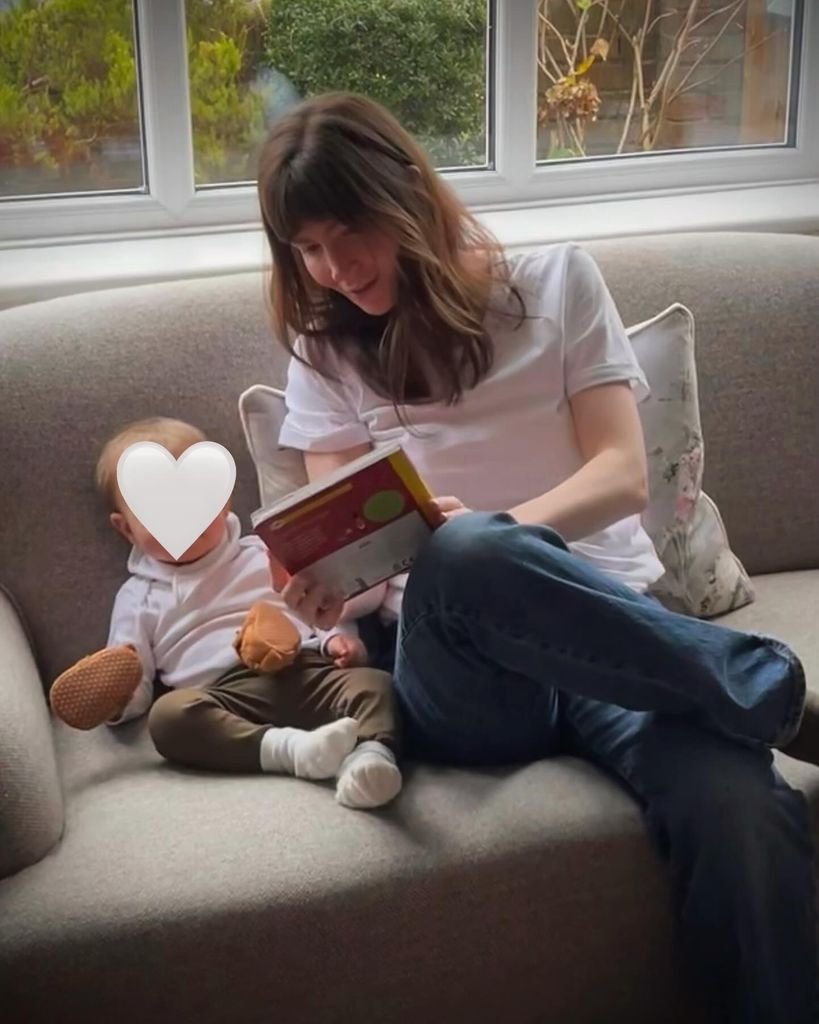 Natasha sat on sofa reading to baby