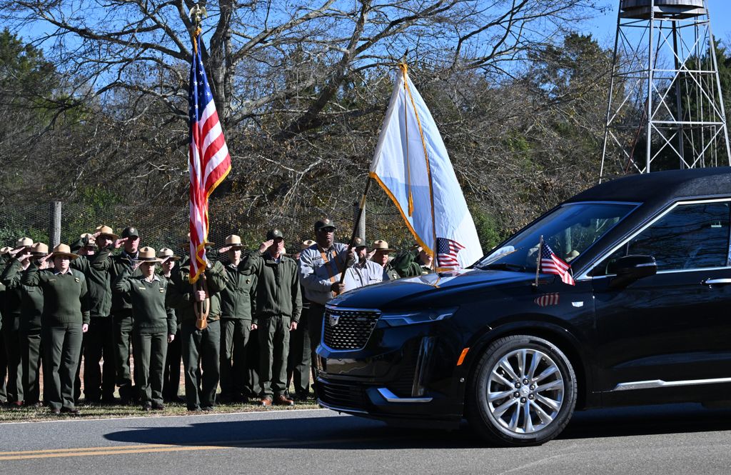 Members of the National Park Service salute the hearse containing the casket of former US President Jimmy Carter