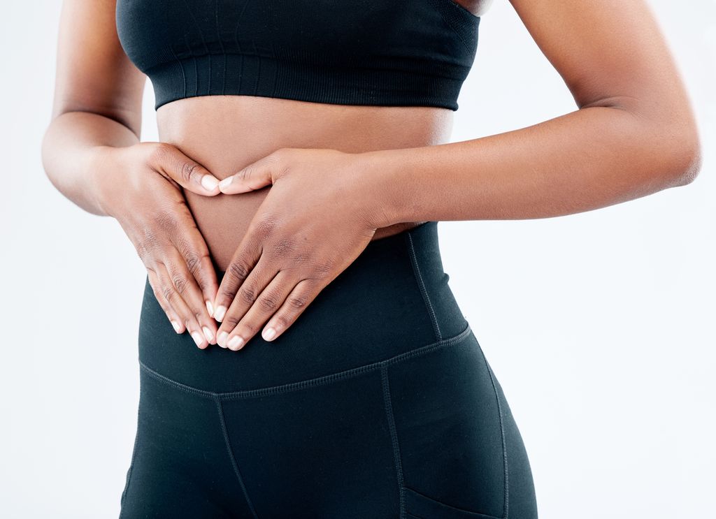 a woman in black activewear holding her stomach