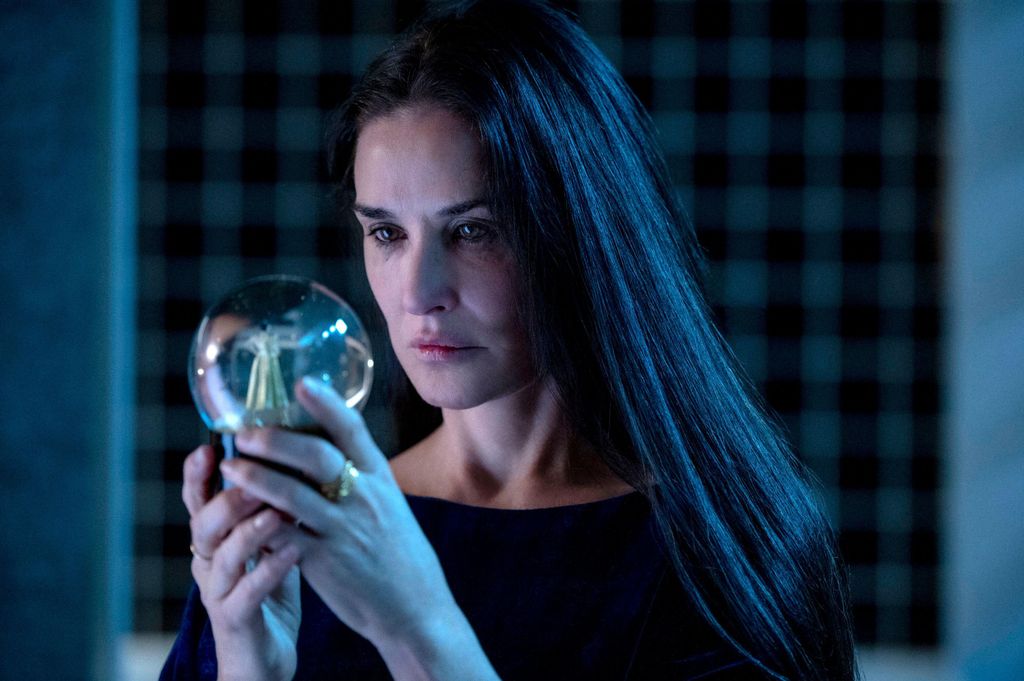 Demi Moore looks into a snow globe in still from The Substance