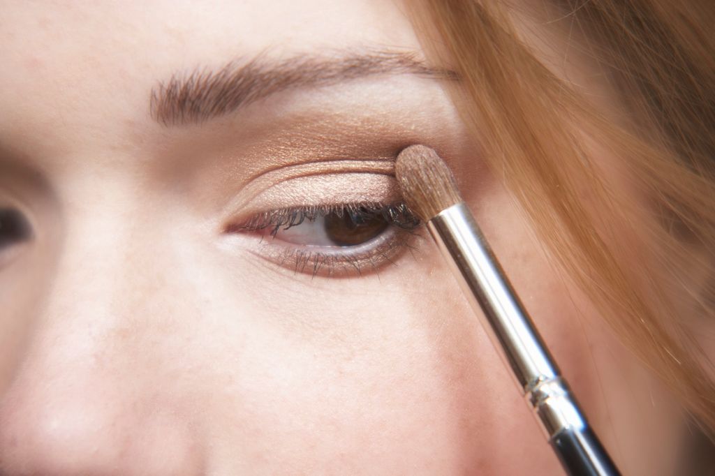 woman applying eyeshadow, close-up of eye