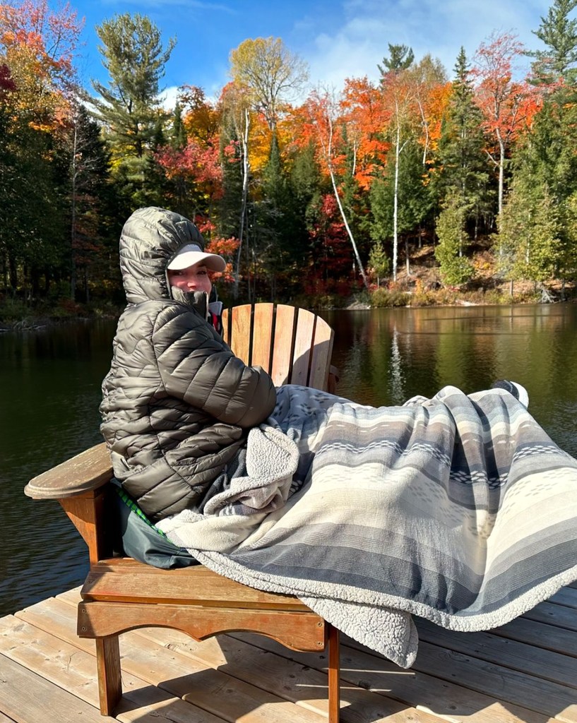 Photo shared by Shania Twain on Instagram October 14, 2024, Canadian Thanksgiving, of her cozied up sitting by the lake