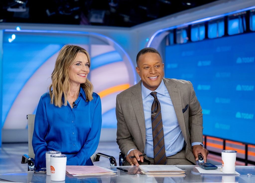 Female and male TV hosts sitting behind desk 