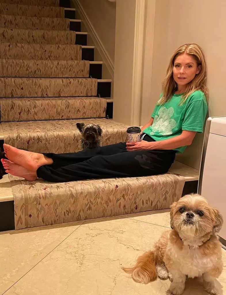 kelly ripa sitting on stairs near pet dogs