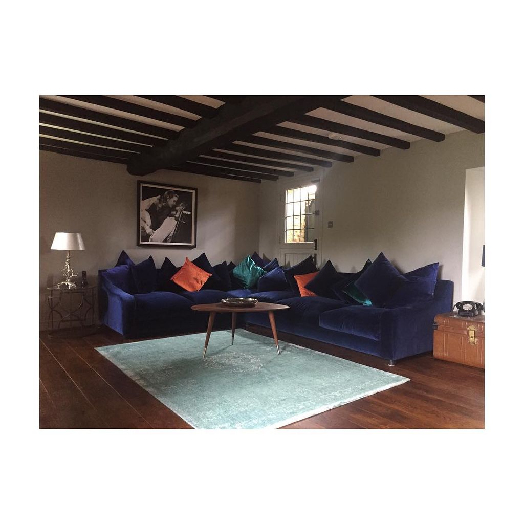 A spacious living room with beams on the ceiling and a soft blue sofa 