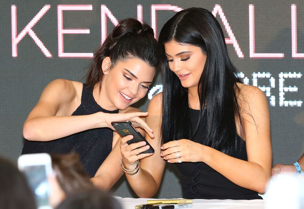 Kendall and Kylie Jenner looking at their phone in 2015