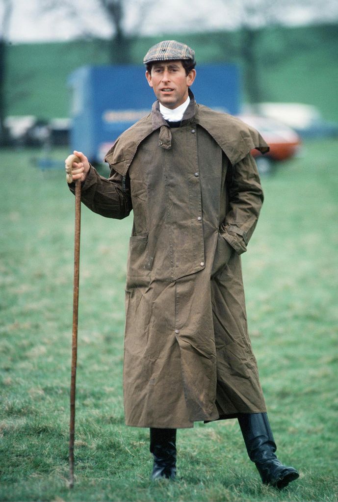 man in long wax coat with walking stick 