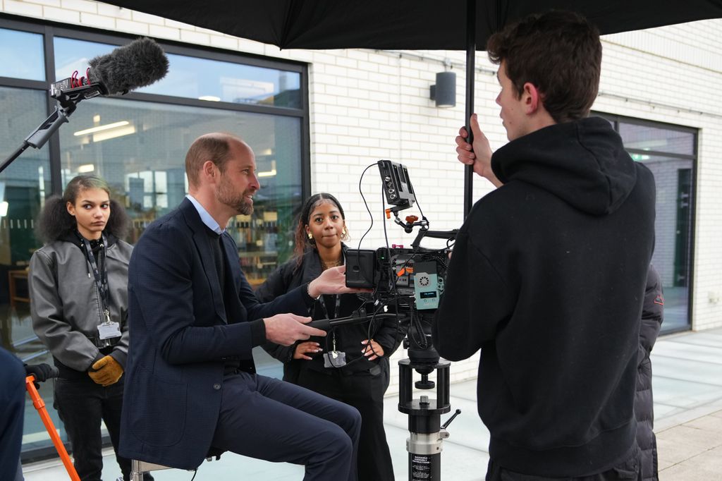 Prince William sat on a dolly with three students standing around him