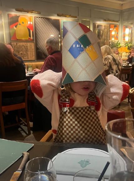 A young child with a menu wrapped around his head