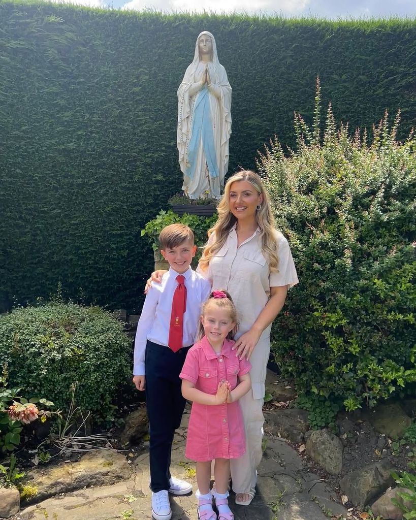 Izzi standing in her garden with her two children smiling for a photo