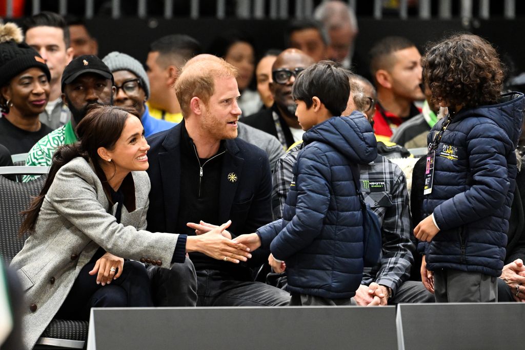 Meghan, Duchess of Sussex and Prince Harry, Duke of Sussex shakes hands with twio young boys during the wheelchair basketball match