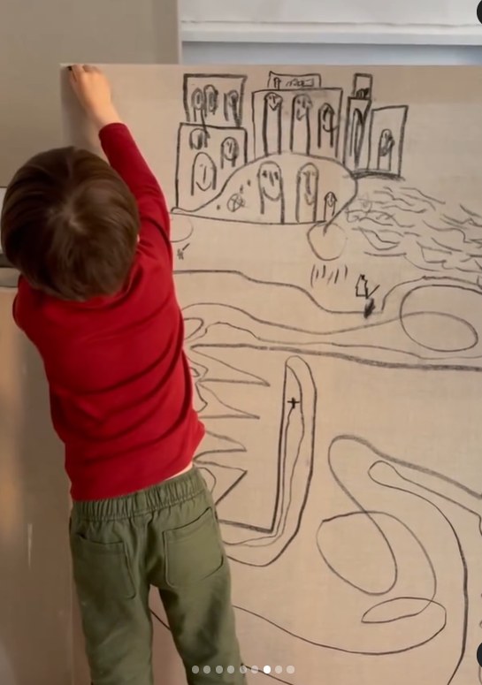 child from back drawing on big canvas