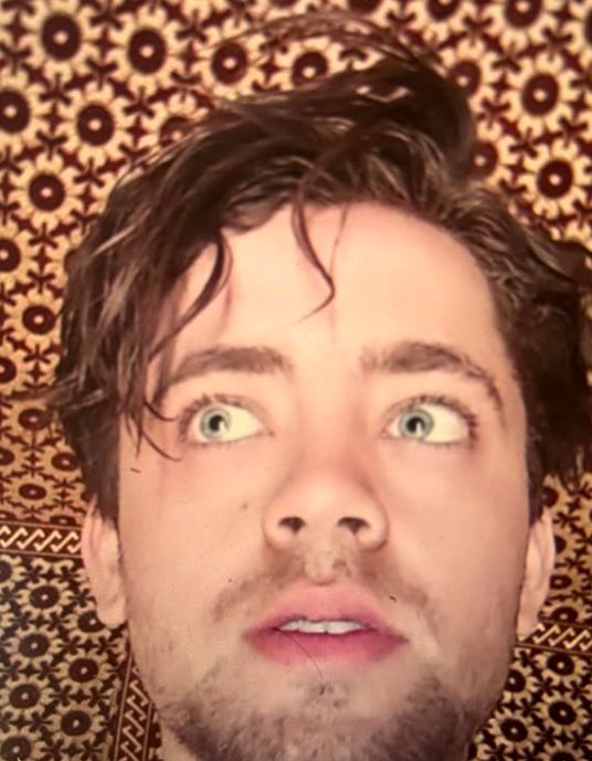 A close-up of a young man's head in a tent