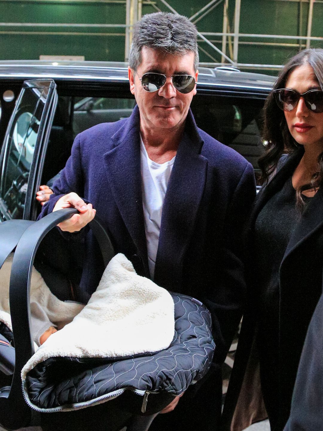 Simon Cowell and Lauren Silverman with a baby carrier