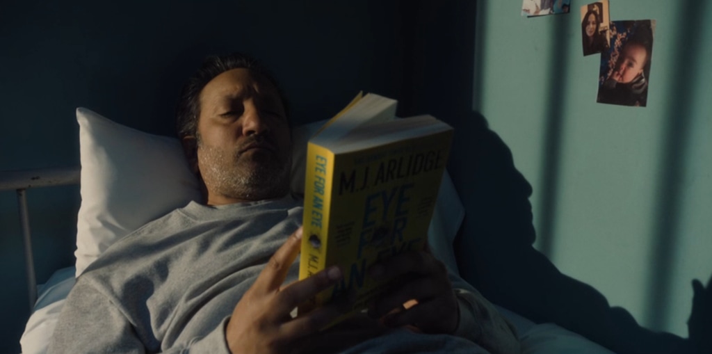 Man reading book in bed in dimly-lit room