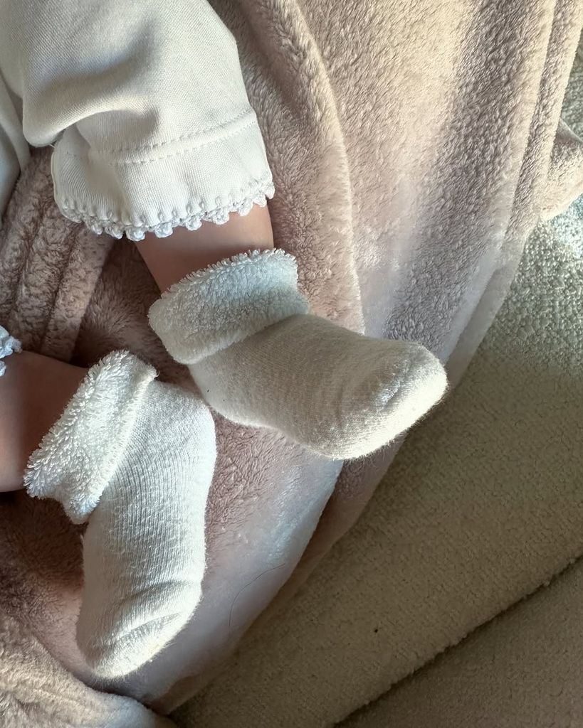 A birds-eye view shot of baby feet in fluffy booties with a blanket