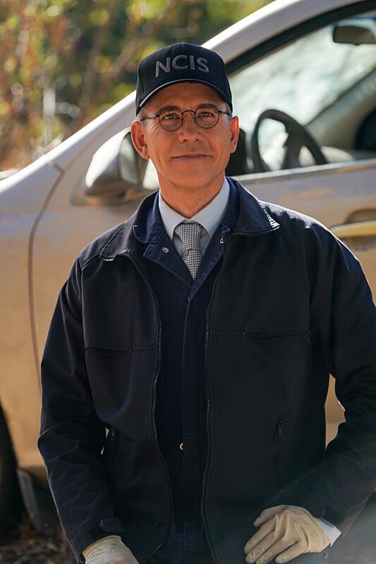 Man in navy suit wearing cap that says NCIS