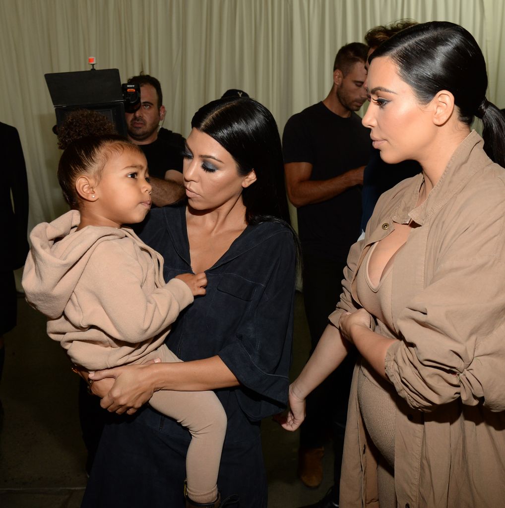 North West being held by Kourtney Kardashian with Kim standing nearby