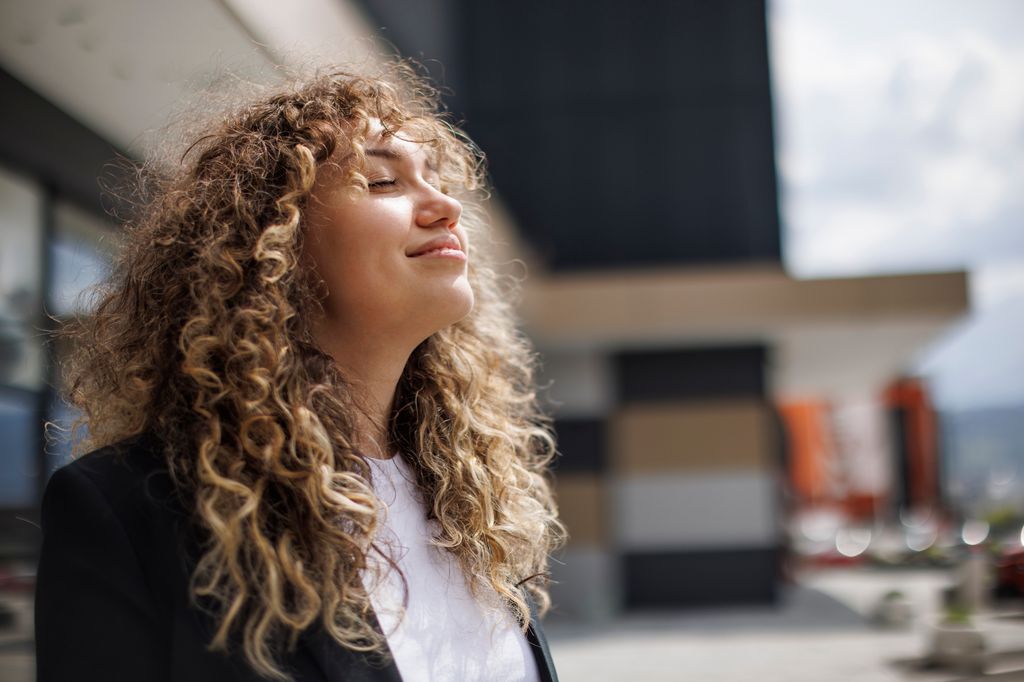 Business woman relaxing outdoors smiling into the sun 