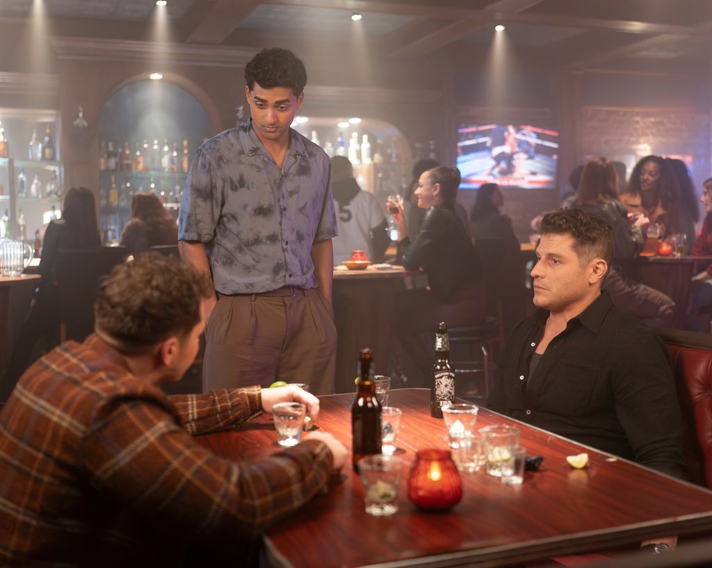 Ravi stands over Tommy and Buck as they sit in a bar in a still from 911